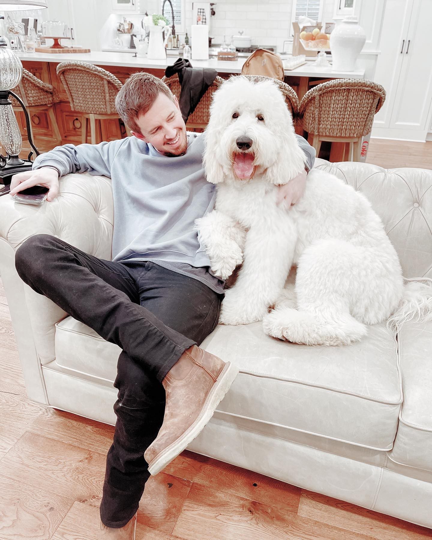 man with large f1b white English teddy bear golden doodle on couch